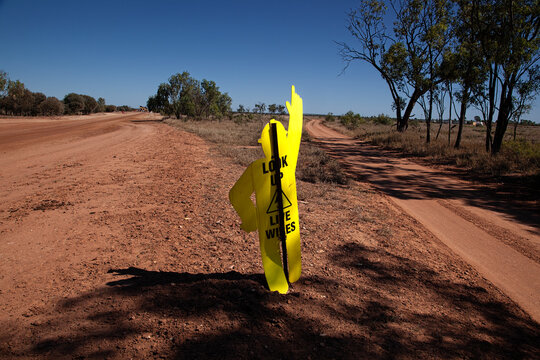 Yellow Cardboard Man Pointing Up Warning About Power Lines Nearby On A Road Construction Site.