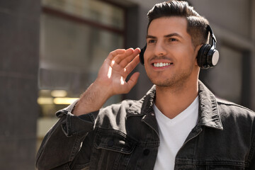 Handsome man with headphones listening to music on city street