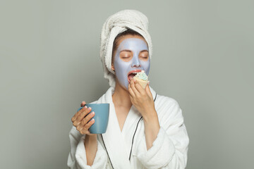   Female routine and breakfast. Young cute woman in cosmetic face mask eating breakfast and...