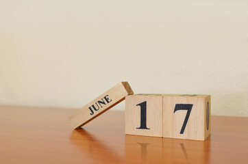 June 17, Date design with calendar cube on wooden table and white background.	
