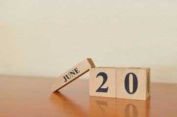 June 20, Date design with calendar cube on wooden table and white background.	
