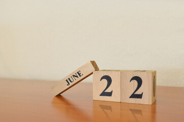 June 22, Date design with calendar cube on wooden table and white background.	
