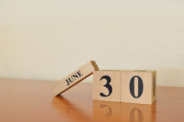 June 30, Date design with calendar cube on wooden table and white background.	
