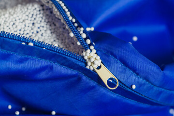 Electrified lightweight foam filler stuck to the zipper, hands, blue fabric