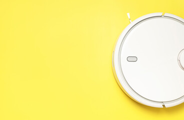 Modern robot vacuum cleaner on yellow background flat lay. New technologies, quick house cleaning,...
