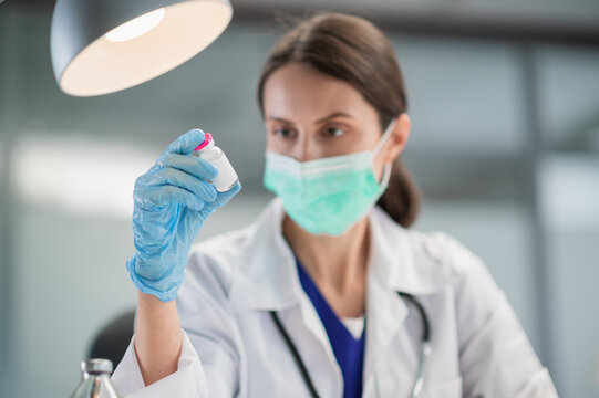 In The Treatment Room Of The Hospital, A Nurse Is Preparing To Vaccinate The Population Against Covid-19, Holding A Vaccine In Her Hand