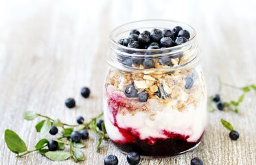 healthy breakfast in a small jar - blueberries, yogurt, granola, muesli, blueberry berry syrup.