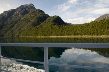 mirror of water, with reflection of the mountains and railing of a boat