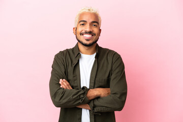 Young Colombian handsome man isolated on pink background keeping the arms crossed in frontal...