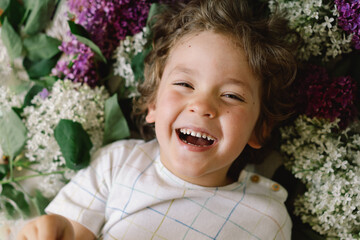Portrait of a happy boy in lilac flowers. Happy childhood.