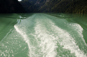 Green waters with wake of the catamaran in Puerto Alegre with mountains in the background