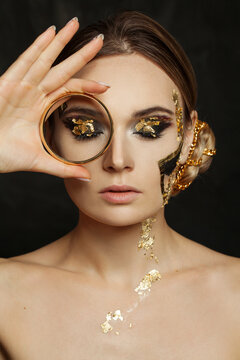 Beautiful Woman With Golden Makeup Holding Gold Bracelet On Black Background