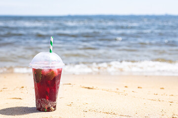 ice drink red lemonade soda on the beach cherry or strawberry fresh juice, sea coast shore, summer surf wave background refreshing relax positive mood vacation top view