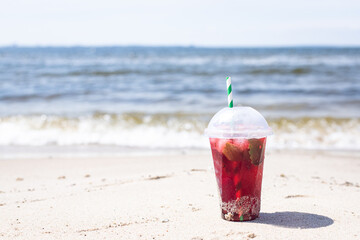 ice drink red lemonade soda on the beach cherry or strawberry fresh juice, sea coast shore, summer surf wave background refreshing relax positive mood vacation top view