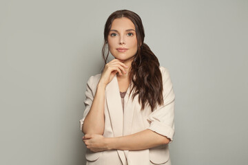 Portrait of friendly businesswoman in white suit on gray background. Perfect smart business lady