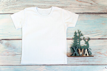 Christmas kid shirt mockup - white tshirt on wooden background. Stock photo