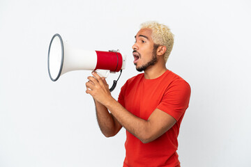 Young Colombian handsome man isolated on white background shouting through a megaphone to announce...