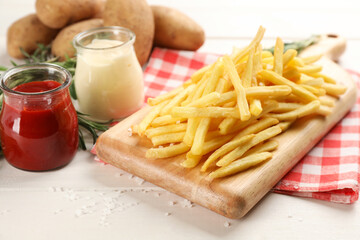 Delicious french fries served on white wooden table