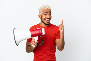 Young Colombian handsome man isolated on white background holding a megaphone and intending to realizes the solution