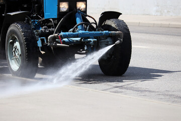 Watering machine pours water on the road. Disinfection of city streets during the covid-19 coronavirus pandemic