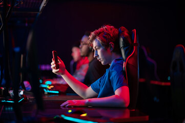 A young esports player records a video on his phone for his vlog from the training base of his team of gamers