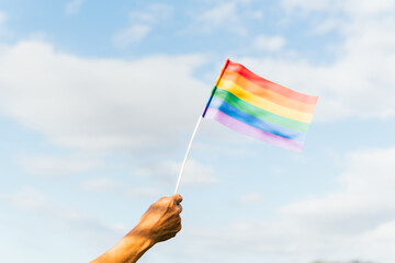 Unrecognizable person hand waving rainbow gay pride flag. activist for the rights of lgbt people.