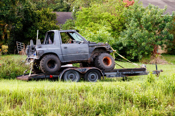 Four wheel drive jeep type truck with oversized jumbo dirt tires on a motor boat trailer rusted,...