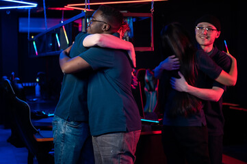 Fototapeta na wymiar After winning the cyber tournament, the guys and the girl hug each other for joy