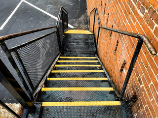 industrial fire escape safety alley stairs steps with bright yellow caution stripes next to retro...