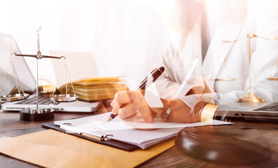 Justice and law concept.Male judge in a courtroom with the gavel, working with, computer and docking keyboard, eyeglasses, on table in morning light