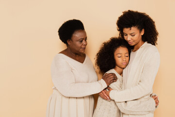 african american mother and grandmother hugging and supporting sad granddaughter on beige background