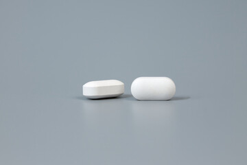 Two pills on a gray background. Pharmaceutical Industry concept