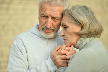 Sad thoughtful senior couple in  park