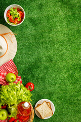 Garden space with picnic basket and food on red cloth. Overhead view - obrazy, fototapety, plakaty