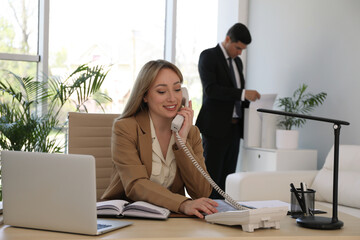 Secretary talking on phone at workplace in office