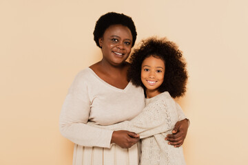 Obraz premium african american grandmother and granddaughter hugging on beige background