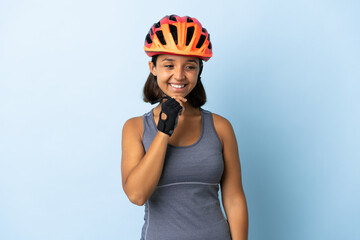 Young cyclist woman isolated on blue background looking to the side and smiling - obrazy, fototapety, plakaty
