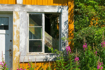 Window of abandoned, ocher yellow house.