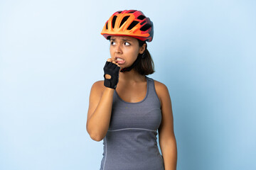 Young cyclist woman isolated on blue background nervous and scared - obrazy, fototapety, plakaty