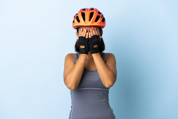 Young cyclist woman isolated on blue background covering eyes by hands - obrazy, fototapety, plakaty