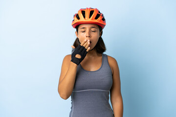 Young cyclist woman isolated on blue background yawning and covering wide open mouth with hand - obrazy, fototapety, plakaty