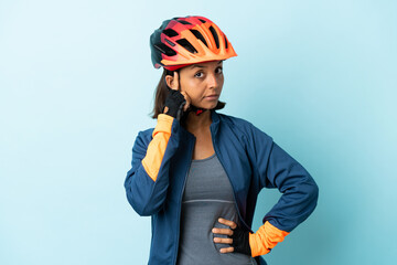 Young cyclist woman isolated on blue background thinking an idea - obrazy, fototapety, plakaty