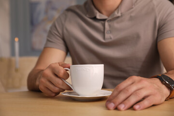Man with cup of coffee at cafe in morning, closeup