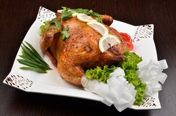 baked whole chicken with salad and lemon, beautifully served in a white plate
