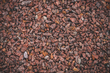 Small red granite rocks as background. Crushed stone for building industry. Abstract small granite stones texture