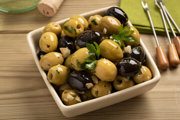 Bowl with green and black olives seasoned with garlic and herbs close up 