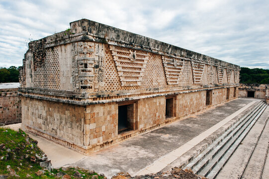Ancient mayan wall with arches with green garden around in Uxmal, Mexico