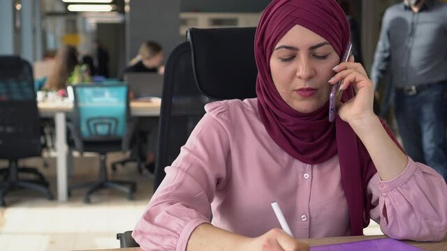 Muslim businesswoman in a hijab works with a multi-racial team. Office Space and Workspace