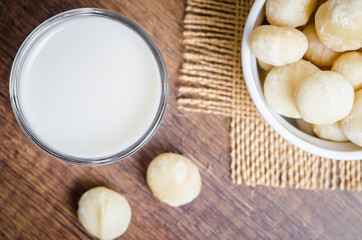 Obraz na płótnie Canvas Macadamia milk in a glass and a bowl of macadamia nuts.