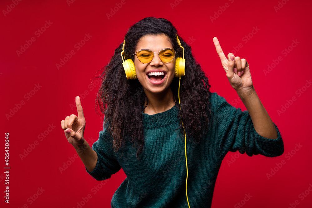 Sticker Photo of cheerful nice dark skin young lady good mood wear headset sunglass dance isolated on red color background